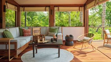 A spacious living area with a wooden floor, a sofa with cushions, a coffee table, and a rocking chair.