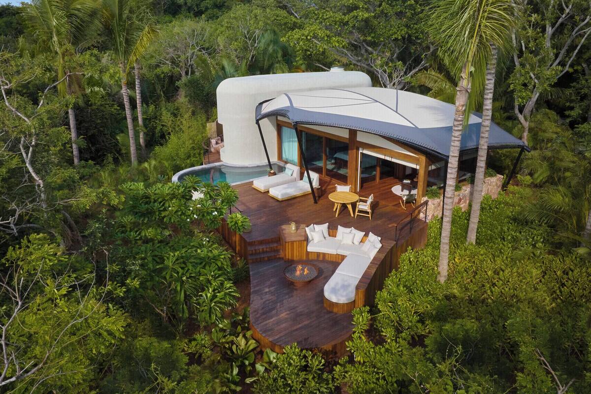 A modern house with a pool, surrounded by lush greenery.