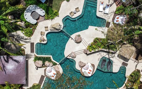 An aerial view of a resort with multiple swimming pools, lounge areas, and tropical landscaping.