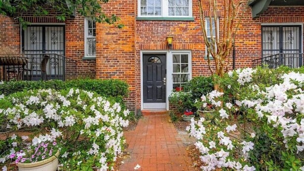 A brick building with a black door and white-framed windows.
