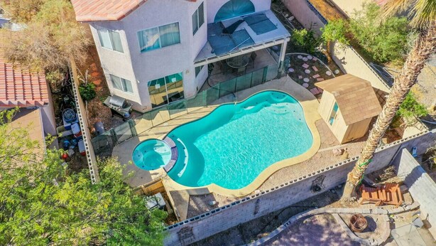 Une maison à deux étages avec une piscine, un patio couvert et une cour arrière clôturée.