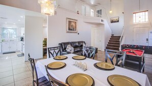 Une salle à manger spacieuse avec un plafond haut, un escalier et une table de baby-foot.