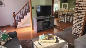 A living room with a TV, sofa, and a dining area with chairs.