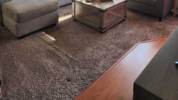 A living room with a sectional sofa, a coffee table, and a ceiling fan.