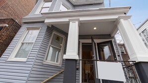 A two-story house with a gray exterior, white trim, and a black metal gate.