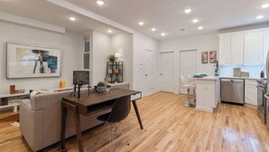 A modern kitchen with white cabinets, a wooden dining table, and a built-in oven.