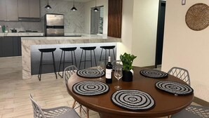 Une cuisine moderne dotée d’un îlot central, de tabourets de bar et de luminaires suspendus.