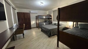 Une petite pièce comprenant des lits superposés, un bureau, une chaise et une armoire.