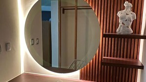 Une salle de bain moderne avec un miroir rond, un meuble-lavabo en bois et un buste décoratif.
