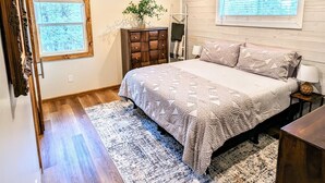 Een slaapkamer met een bed, een houten dressoir, een raam en een dakraam.