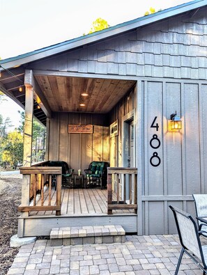 A wooden cottage with a porch, a sign reading "The Cozy Cottage," and the number "408" on the wall. - Relax & Recharge in Cozy Pinetop 2BR Retreat (Pinetop-Lakeside)