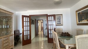 A dining area with a glass table, wicker chairs, and a cabinet with glassware. - R151 - Apart Beachfront (Calafell)