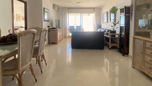 A spacious living area with a dining table, chairs, a sofa, and a kitchen area with cabinets and appliances. - R151 - Apart Beachfront (Calafell)