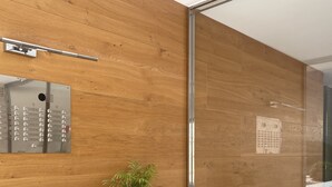 A modern interior with a wooden wall, a glass door, a plant, and a control panel. - R151 - Apart Beachfront (Calafell)