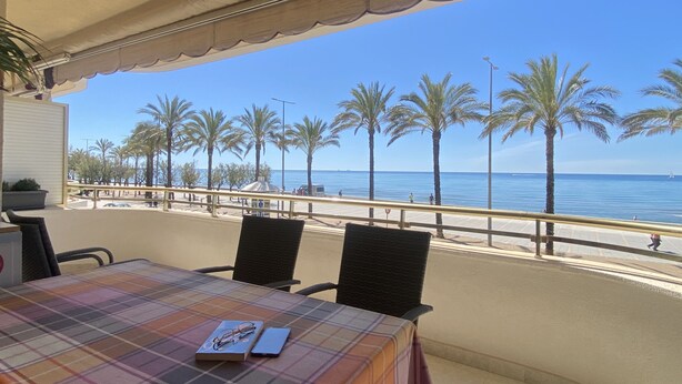 A table with a plaid tablecloth, chairs, and a view of the beach and ocean. - R151 - Apart Beachfront (Calafell)