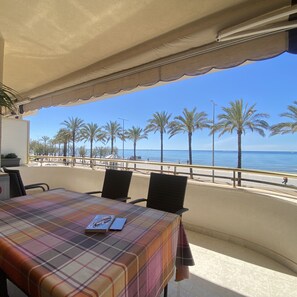 A table with a plaid tablecloth, chairs, and a view of the beach and ocean. - R151 - Apart Beachfront (Calafell)