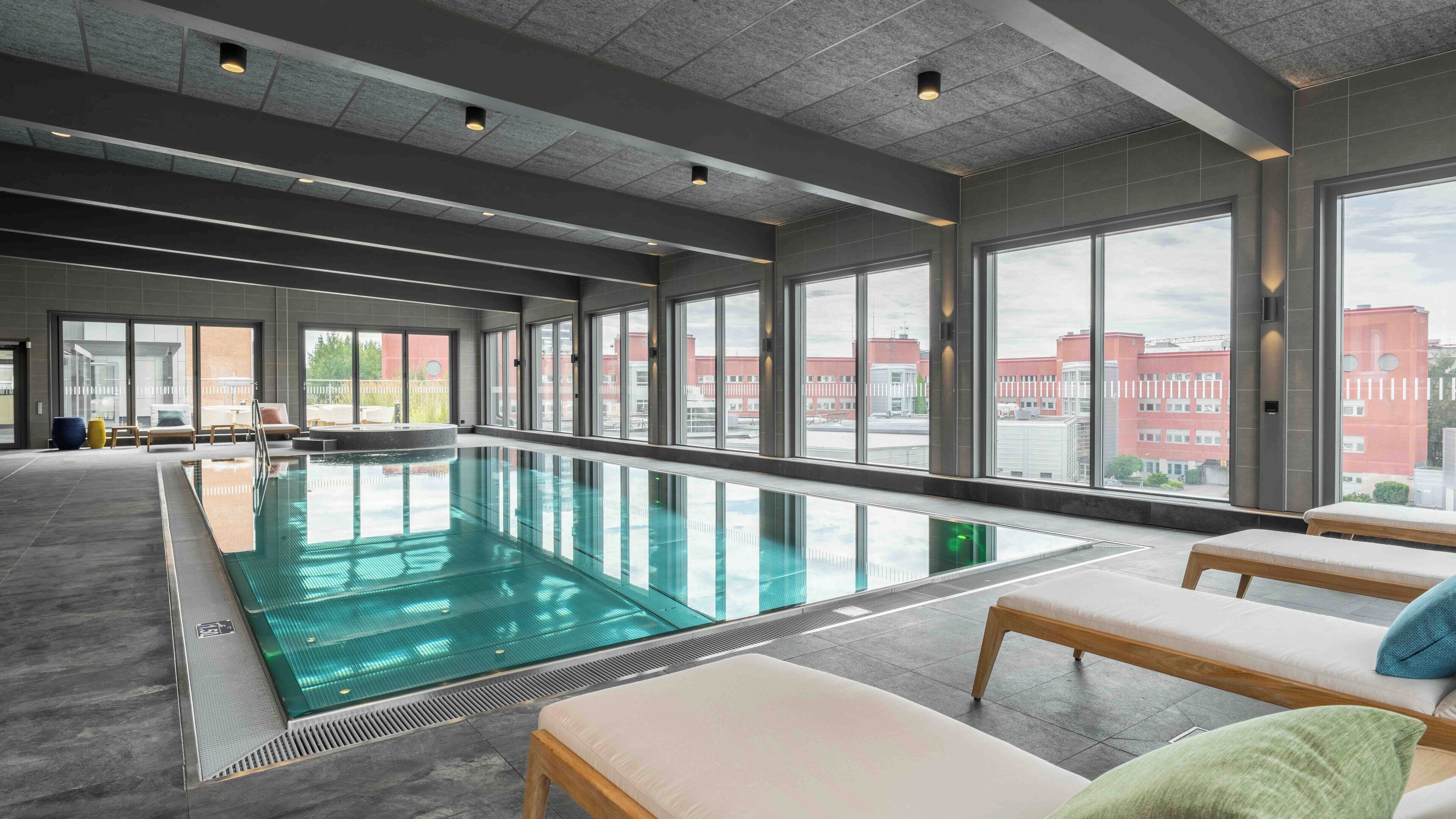 A modern indoor swimming pool with clear views of the cityscape through large windows.