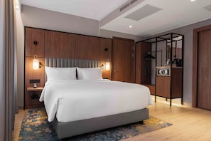 A modern hotel room with a large bed, wooden headboard, bedside tables, and a built-in wardrobe. - voco Stockholm Kista by IHG (Kista)