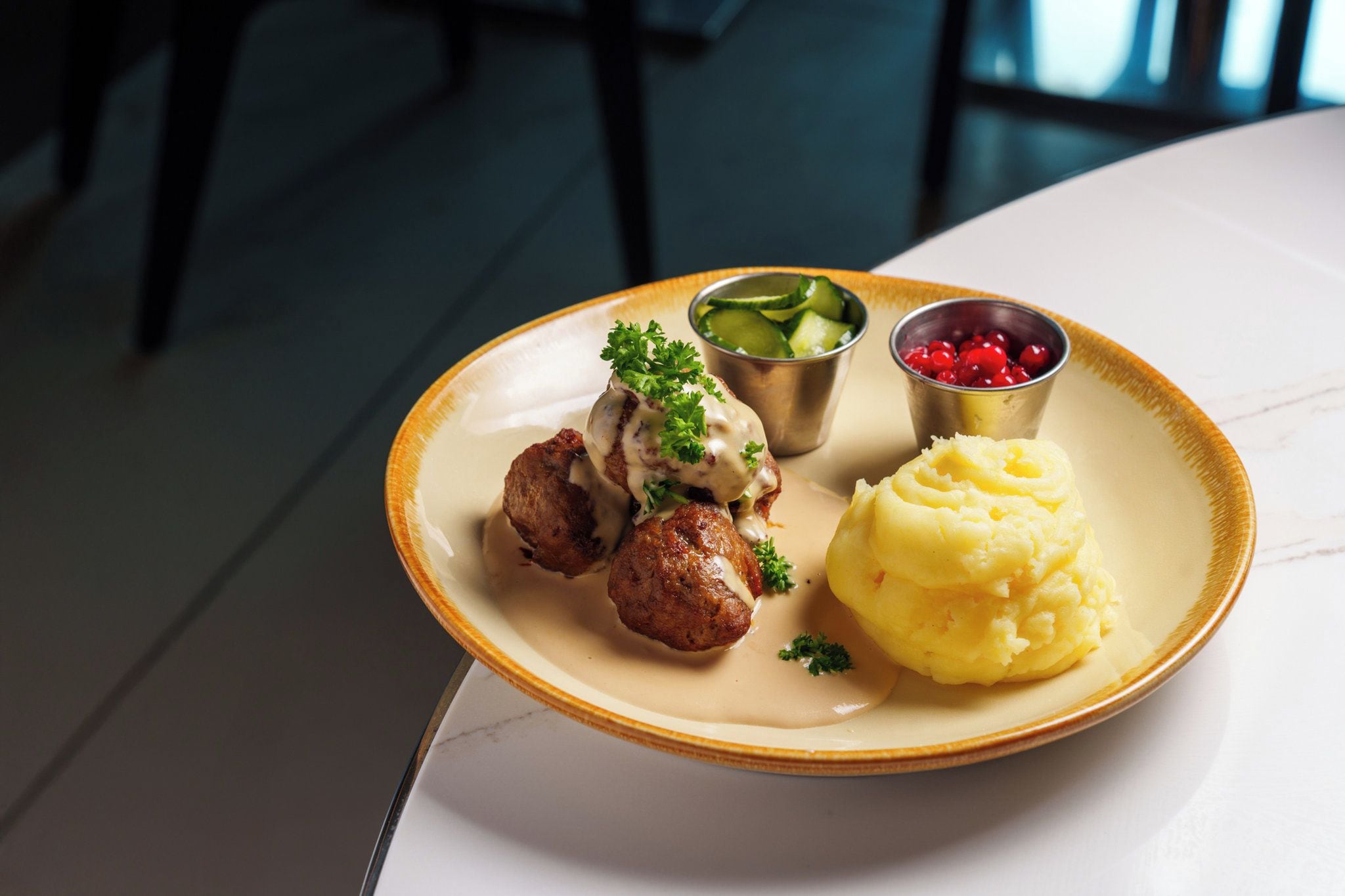 A plate with meatballs, mashed potatoes, and two side dishes on a table.