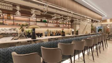 Un espace bar moderne doté d’un long comptoir, de tabourets et d’une variété de bouteilles et de verres.