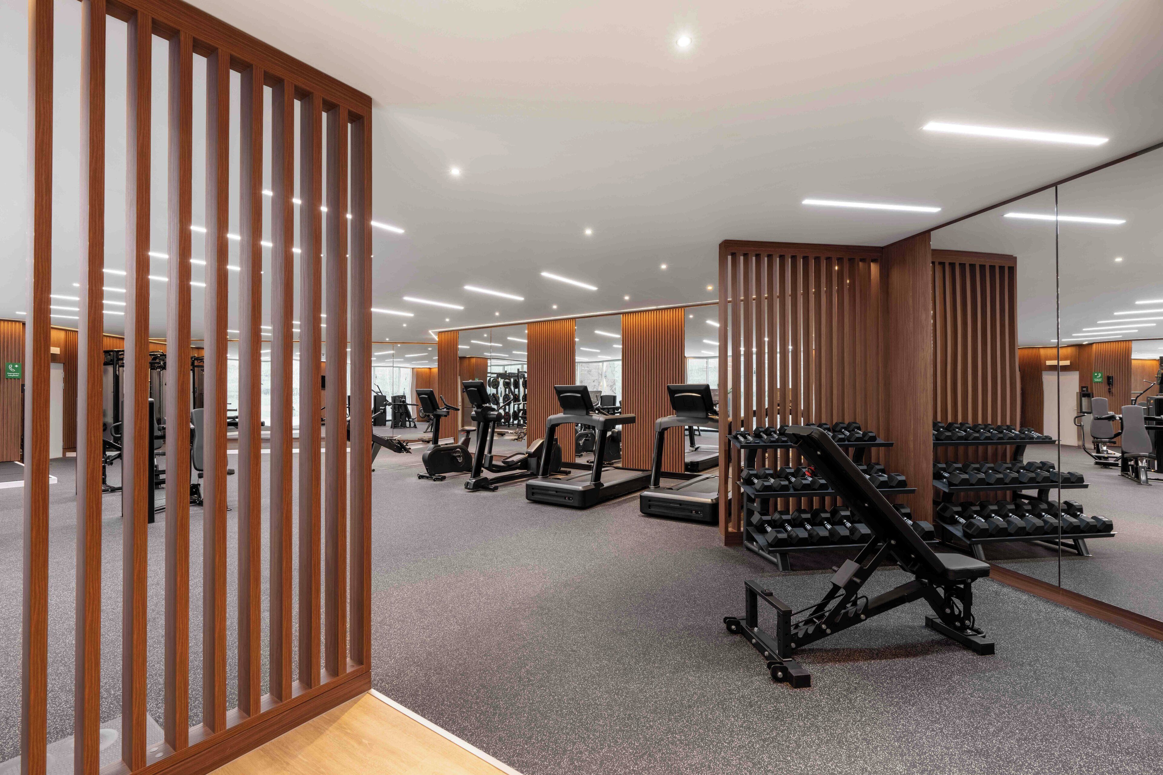 A modern gym with treadmills, elliptical machines, and free weights.