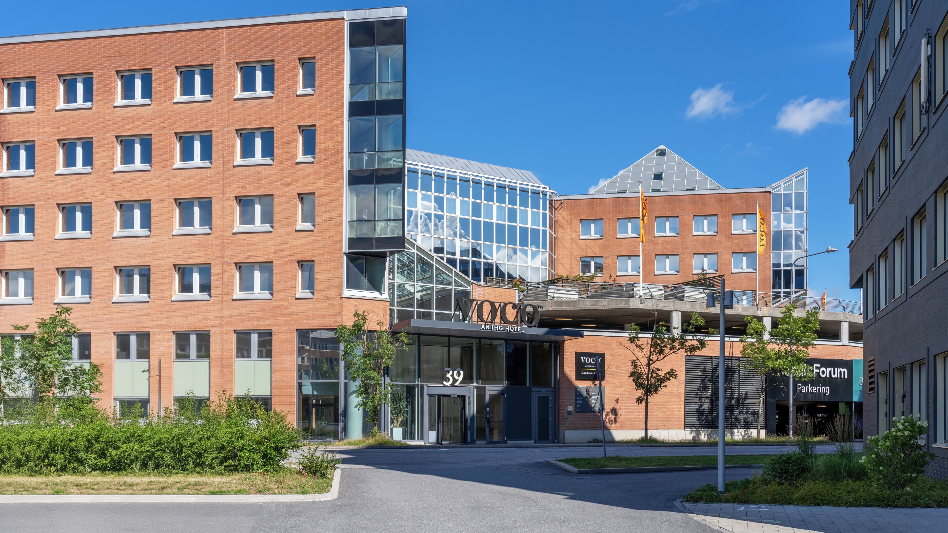 Een modern hotel met een glazen gevel, een bakstenen gebouw met een plat dak en een parkeergarage.