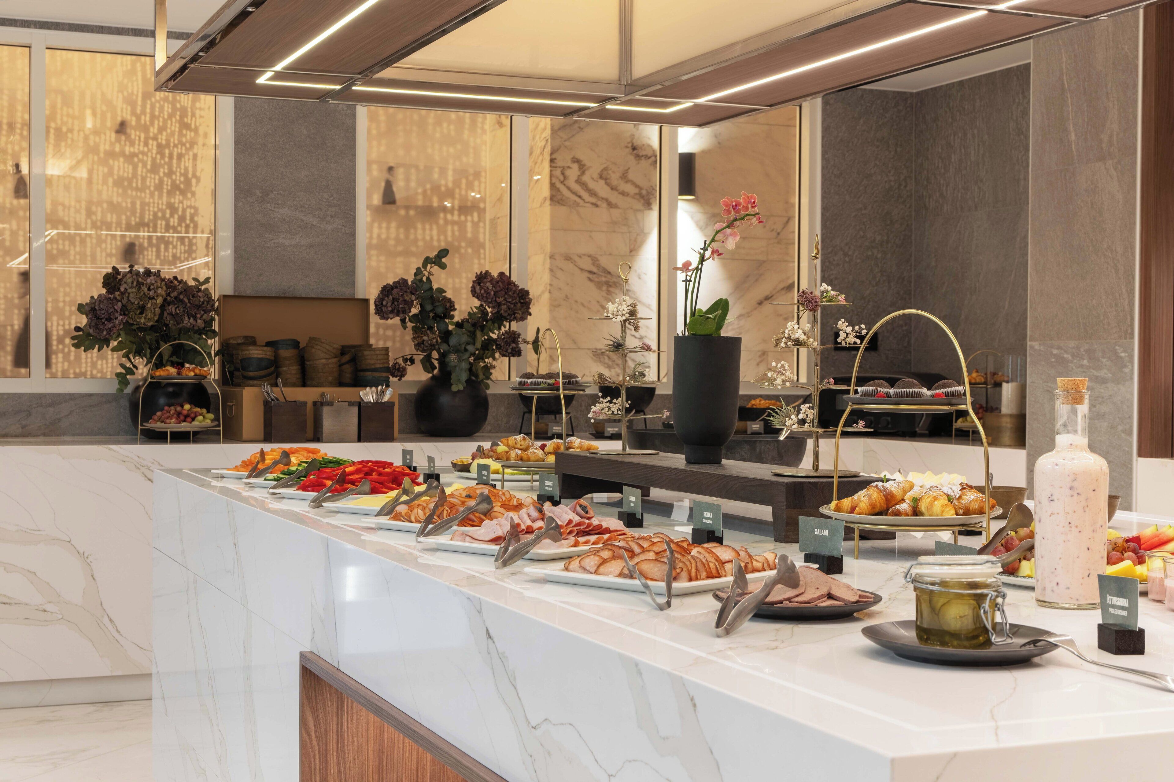 A buffet with various food items and a large vase of flowers.