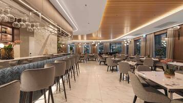 A modern restaurant with a bar area, marble flooring, and contemporary furniture.