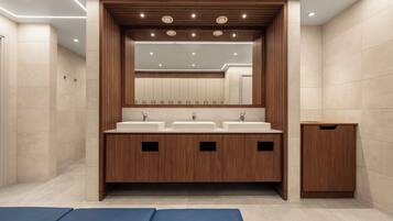 A modern bathroom with three sinks, wooden cabinetry, and a large mirror.