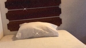 A bed with a white pillow and a headboard with a light fixture above it. - Flats Paraty (Patitiba Paraty)
