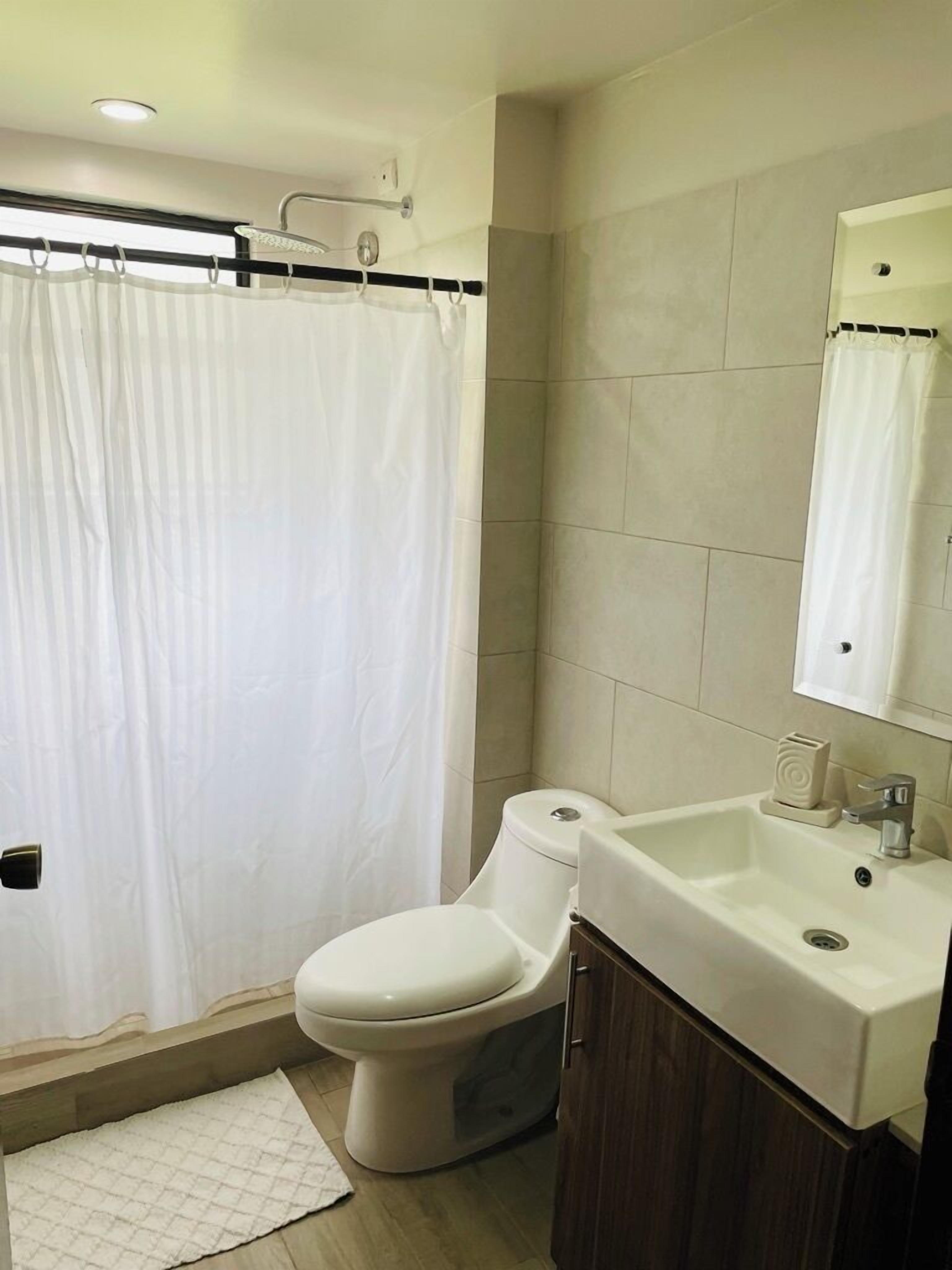 Un baño con inodoro, lavamanos y cortina de ducha.