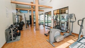 A gym with exercise equipment, a weight rack, and large windows. - Apartamento Ganesha Liberia (Liberia)