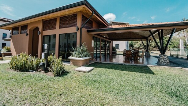 A modern house with a covered patio, a lawn, and a small garden with cacti. - Apartamento Ganesha Liberia (Liberia)
