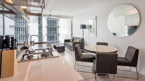 A modern kitchen with a central island, dining area with chairs, a round table, and a large mirror on the wall. - 2 Bedroom Apartment with Parking, Pool, Gym (Fortitude Valley)