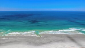 A beach with clear turquoise waters and a sandy shore.