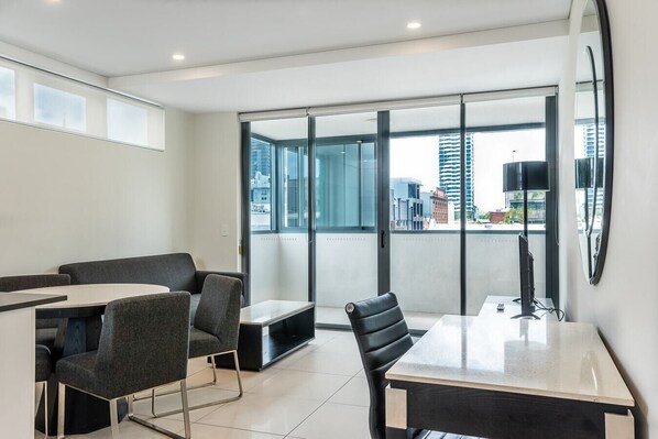 A modern office space with a glass wall, a round table, and two chairs.
