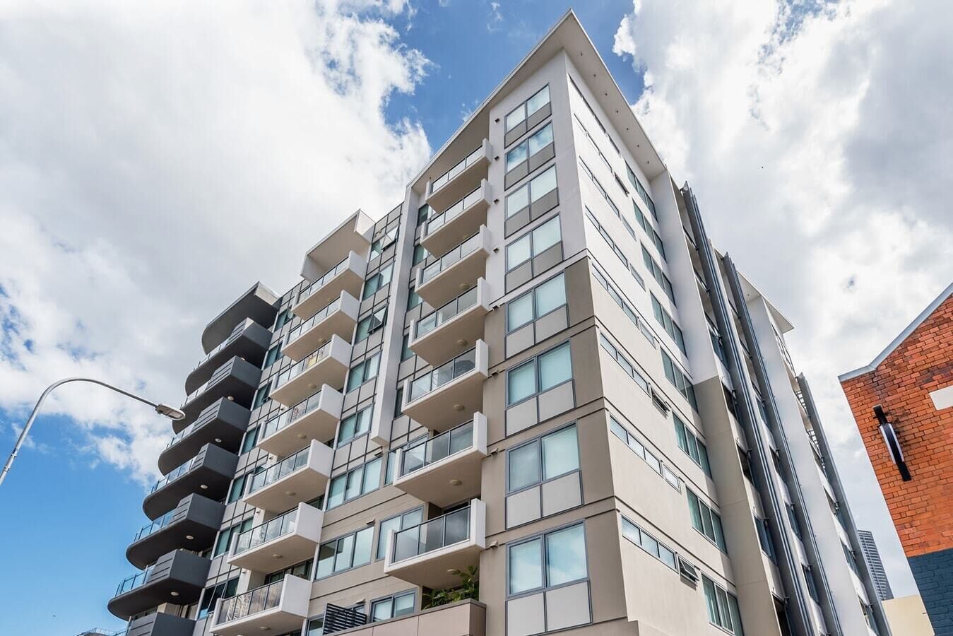 Un edificio residencial de varios pisos con balcones, ventanas amplias y un estilo arquitectónico moderno.