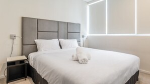 A modern hotel room with a large bed, a bedside table, and a nightstand.