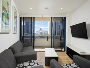Una sala de estar moderna con un sofá, una mesa de centro y un televisor montado en la pared.