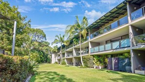A modern multi-story hotel with balconies, surrounded by lush greenery and palm trees. - Baden 58 - Rainbow Shores. Pools, outdoor spa, walk to beach. Tennis court (Rainbow Beach)