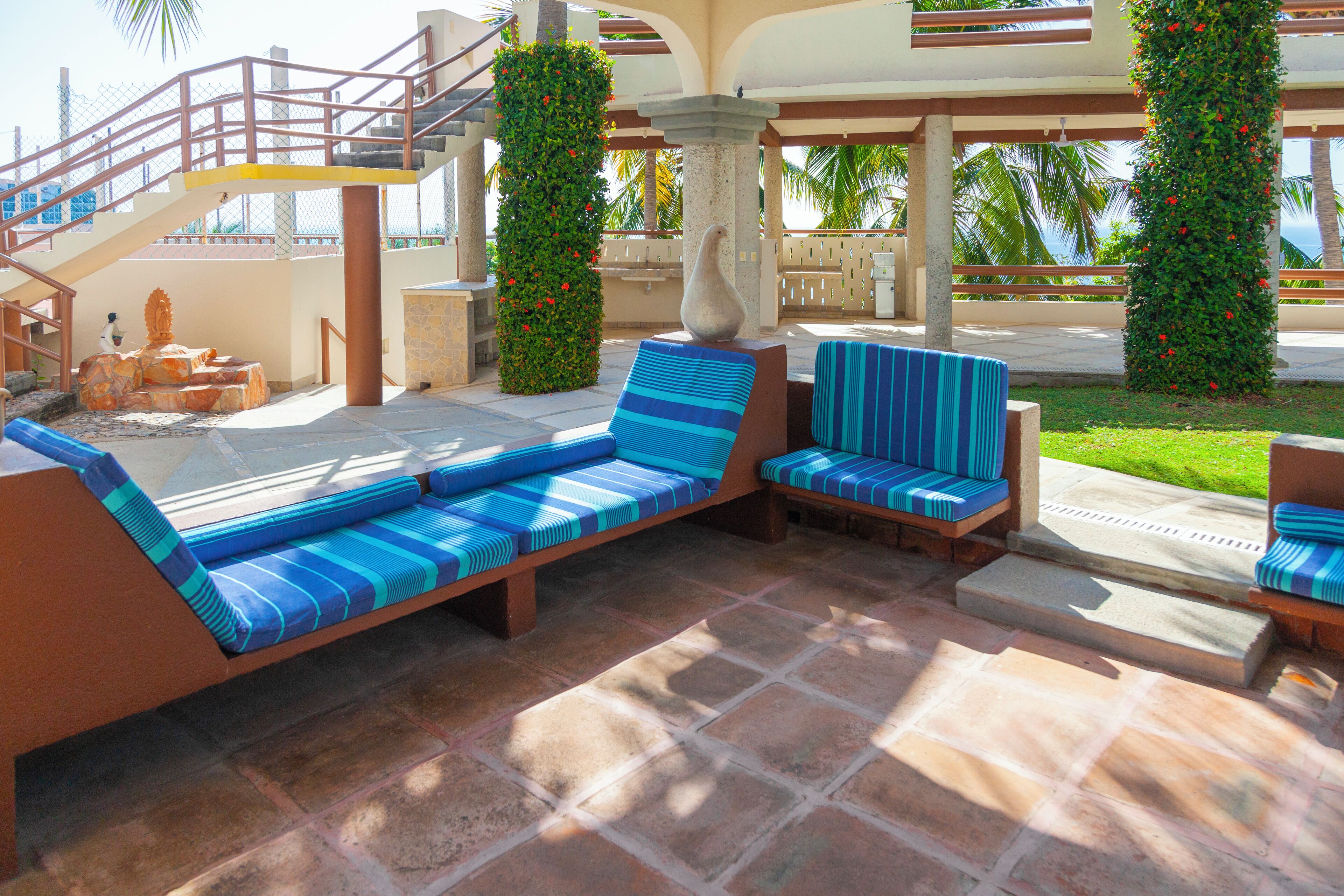 Zona de piscina con sillones de descanso, un banco de piedra y una escalera.