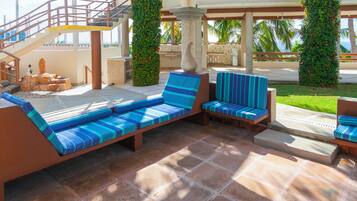 Zona de piscina con sillones de descanso, un banco de piedra y una escalera.