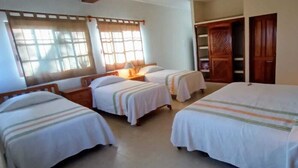Een hotelkamer met vier bedden, houten hoofdeinden en een grote inbouwkast.