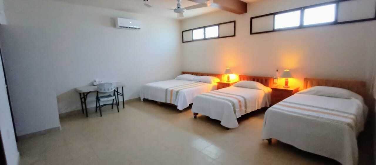 A hotel room with three single beds, a desk, and a chair.