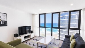 Ein modernes Wohnzimmer mit großem Fenster, Flachbildfernseher, einer Couch und einem Couchtisch.