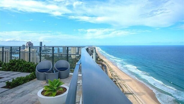 Ein Balkon mit Blick auf Strand und Meer, mit Kübelpflanzen und modernen Stühlen.