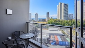 A balcony with a table and chairs, a city view, and a clear sky.