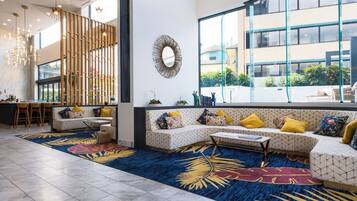 A modern interior with a seating area, a dining space, and large windows offering a view of the outside.