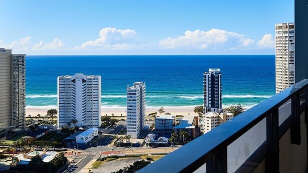 Paisagem costeira urbana com edifícios altos, uma praia e céu azul claro.