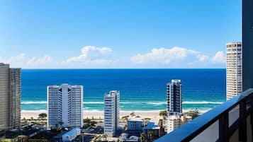A coastal cityscape with high-rise buildings, a beach, and a clear blue sky.
